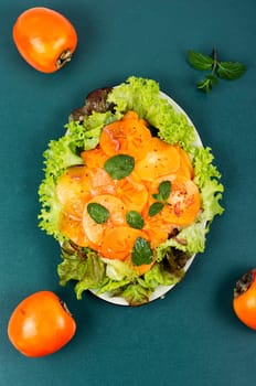 Dietary fruit salad with green salad, fresh persimmon and mint.