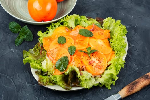 Dietary fruit salad with green salad, fresh persimmon and mint.