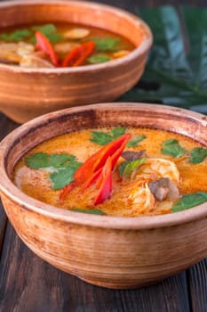 Bowls of tom yum soup on wooden background
