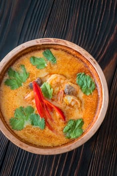 Bowl of tom yum soup on wooden background