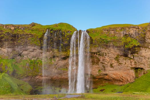 Beautiful Seljalandsfoss waterfall in summer sunny day with the green grass field in Iceland.