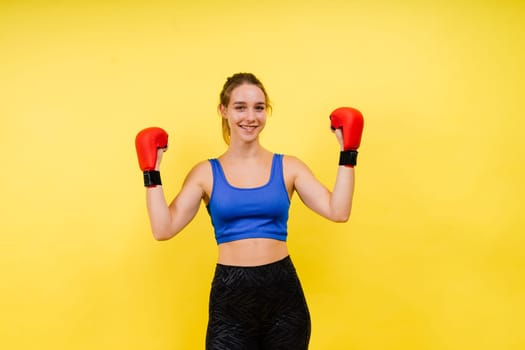 Woman boxer in gloves training on a grey and yellow background