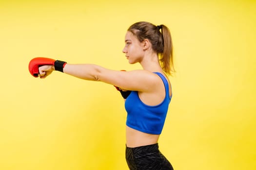 Woman boxer in gloves training on a grey and yellow background