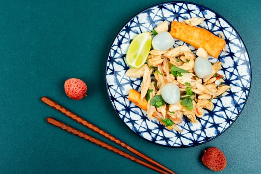Exotic salad with peeled lychee and chicken breast. Asian food on wooden table.