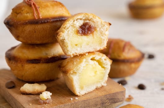 Pasticciotto leccese pastry filled with egg custard cream and sour cherry jam. Pieces of pasticiotto on a wooden board, typical apulian breakfast, close up. Table decorated with coffee beans
