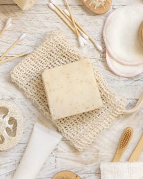 Organic handmade beige soap bars on soap saver bag near hygiene Items - natural sponges, bamboo toothbrushes and cotton swabs top view. Natural herbal products facecare