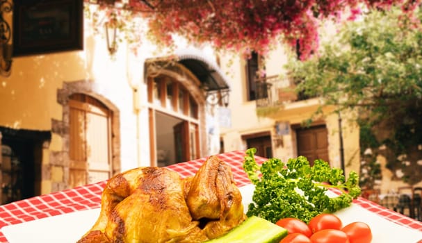 Grilled fresh fried chicken with vegetables on a white plate on table with red checkered table cloth over a blurred restaurant background. Meat on barbecue grill.