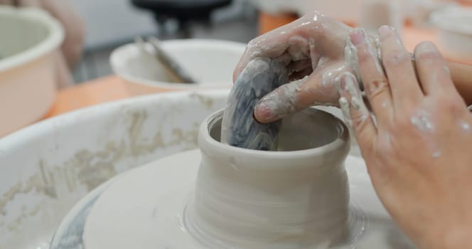 Student work on making ceramic pot on turning pottery wheel