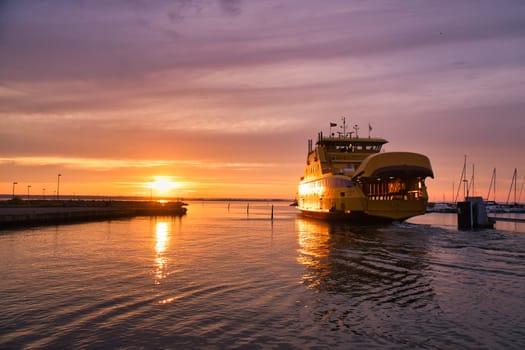 Ferry leaving harbor to Visingsoe island on Vaettern lake for sunset. Lighthouse in the background. Landscape shot from Scandinavia