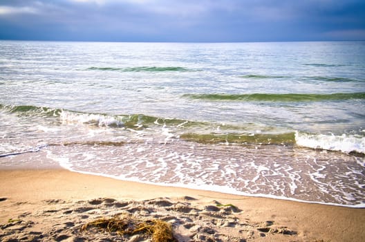 On the coast of the Baltic Sea. Waves roll onto the sandy beach. Nature photo by the sea