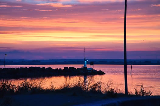 Sunset in Sweden at the harbor of lake Vaettern. Lighthouse in the background at dusk. Landscape shot in Scandinavia.