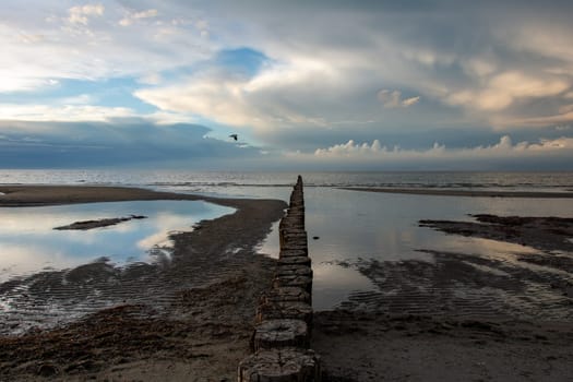 Breakwater on the Baltic Sea coast at low tide with sky and clouds