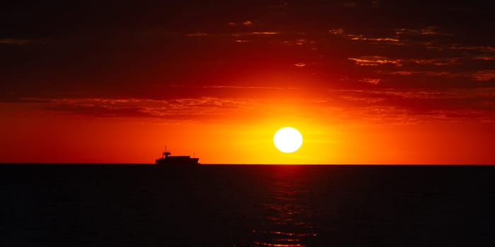 Beautiful orange sunset over the sea, a ship on the horizon