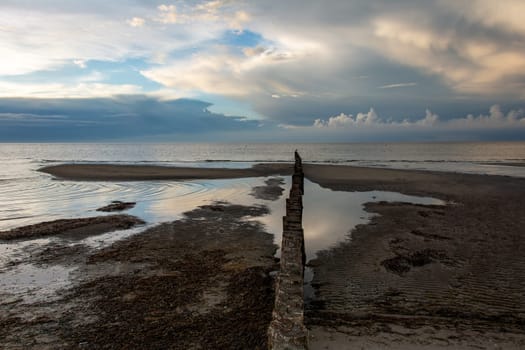 Breakwater on the Baltic Sea coast at low tide with sky and clouds