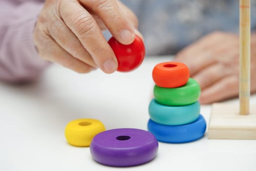 Asian elderly woman playing puzzles game for treatment dementia prevention and Alzheimer disease.