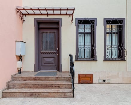 Brightly painted doorway with wooden decorated door, decorated wrought iron windows, and welcoming stairs leading to a cozy home at Istanbul's vibrant Kuzguncuk neighborhood, Uskudar district, Turkey