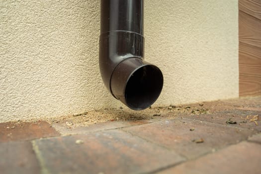 Plastic brown gutter hole near the ground
