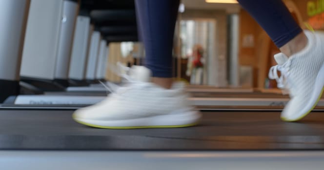 Woman legs run on the treadmill in gym room