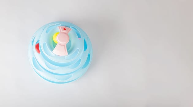 A playful cat engages with a blue tower toy on an isolated white background, featuring a circular turntable and a gripping moving ball. Witness feline intelligence and hunter instincts in action.