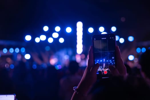 In heart of night concert festival main event lights up with cheering unrecognizable crowd in front of brilliantly illuminated stage. lens flare enhances excitement of this lively music event.