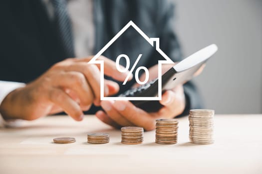 Calculators pressed as hand strategizes home refinance. Desk with house model, buy or rent note. Smart money management to buy property concept. Tax, credit analysis for optimal mortgage payment.