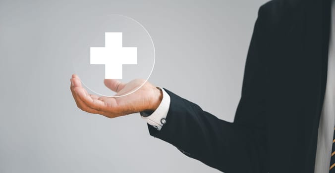 Hand holds a plus sign, representing positivity, benefits, personal development, health insurance. Conveys value enhancement within a corporate framework. Offers a motivating growth perspective.