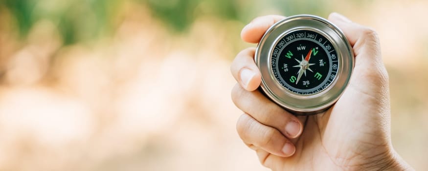 A traveler hand cradles a compass in a park symbolizing the quest for direction and guidance. Amidst nature beauty the compass signifies exploration and discovery.