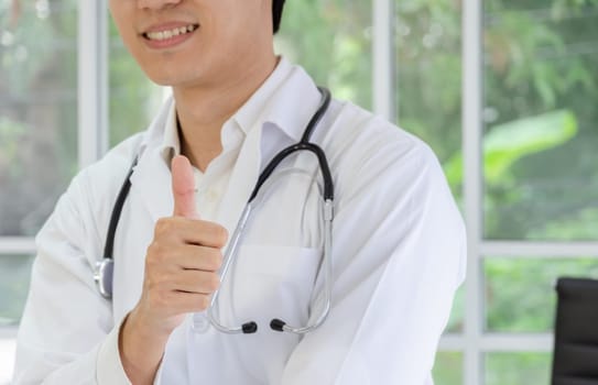 Smiling male doctor in white coat showing thumbs up sign. Healthcare and insurance concept