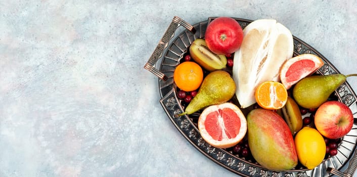 Set of varied, multicolored exotic raw fruits on vintage tray. Top view. Copy space.