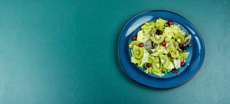 Fresh salad of kiwi, leafy greens, berries and pine nuts on the table. Clean eating.