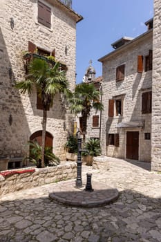 Picturesque small square in the Old Town surrounded by stone tenement houses with a metal well, Kotor, Montenegro