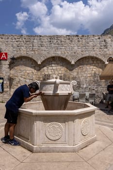 Kotor, Montenegro - June 26, 2023: View of Wood square by Old City Walls with stone decorative fountain