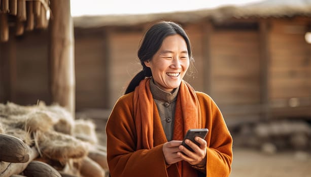 Traditional Chinese woman in village,farm landscape watching on her mobile phone and laughing. Asian elderly woman using smartphone,social media or texting in China beauty