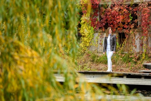 A young beautiful girl walks through an old autumn park