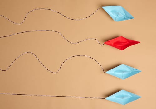 Paper boats on a brown background with paths of movement, representing the concept of individuality. Top view