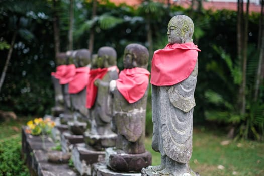 Singapore - July 9 2023: Row of Mini Stone Monk Statues with Red Scarfs