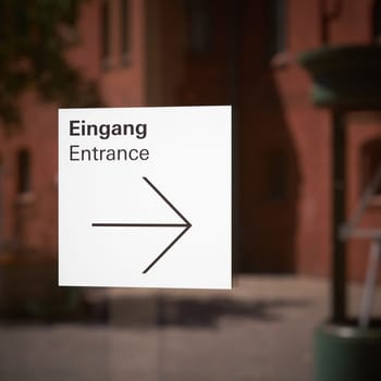 Sign with directional arrow for an entrance at a shop window in Berlin