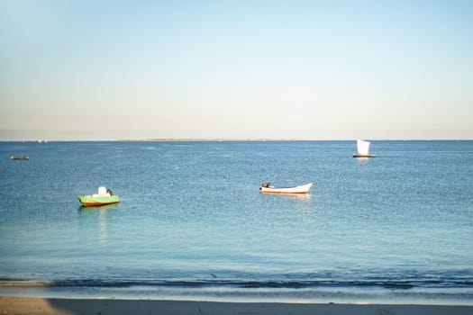 Sun shines on small fishing boats on calm sea near shore in Anakao, Madagascar