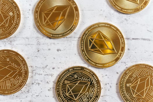 Top down detailed view, golden commemorative EOS - EOSIO  cryptocurrency - coins on white stone board