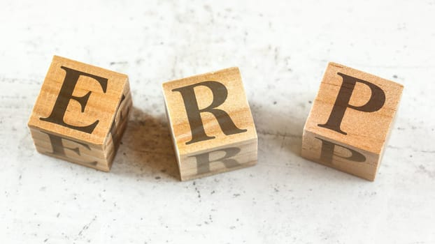 Three wooden cubes with letters ERP - stands for Enterprise Resource Planning - on white board.