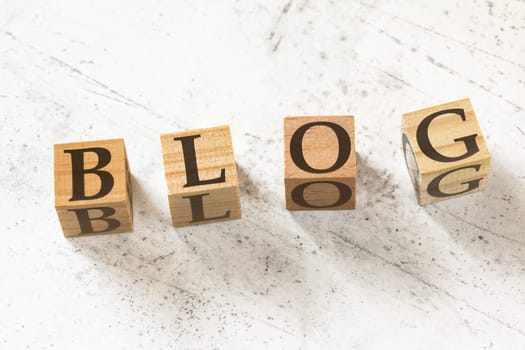 Four wooden cubes with word BLOG on white working board.