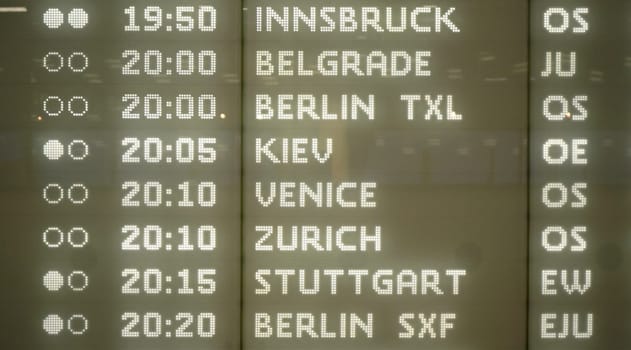 Modern plane departures board with detail on European city destinations typed in illuminated letters at Schwechat airport