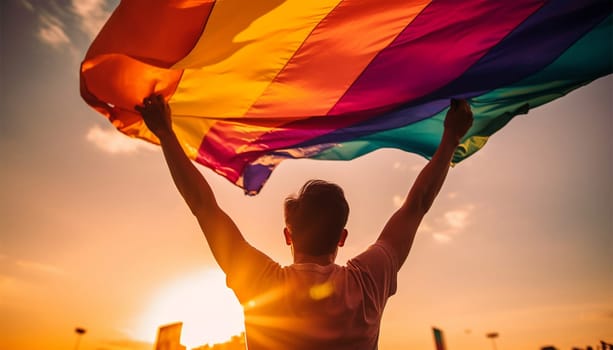 LGBTQ person holding rainbow flag back view in sunlight. copy space, concept for calling all people to support and respect the gender diversity, human rights and to celebrate lgbtq in pride month. Proud lesbian,gay,transgender or bisexual colorful