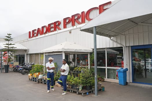 Antananarivo, Madagascar - April 24, 2019: Two employees standing in front of Leader Price supermarket where plants are displayed. This French discount store has branches in many African countries