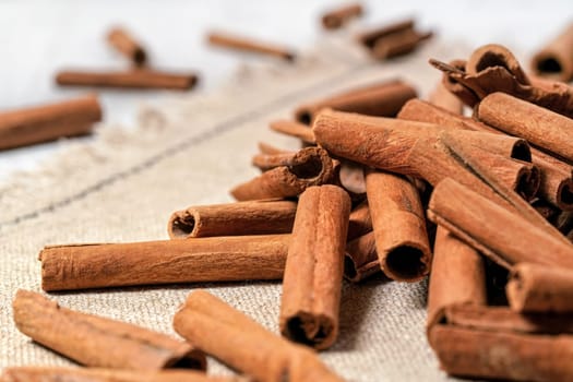 Macro photo - Heap of cinnamon bark sticks on linen tablecloth.