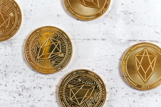 Top down view, golden commemorative EOS - EOSIO  cryptocurrency - coins on white stone board