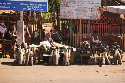 Toliara, Madagascar - May 05, 2019: Unknown Malagasy locals selling food - brown tubers - at street market on sunny day. There are not many shops, goods are usually sold by the road in this region.