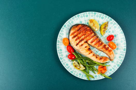 Roasted salmon garnished with potatoes and green beans. Grilled fish.