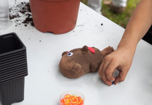 Grass heads workshop for children. Kid placing googly doll eye