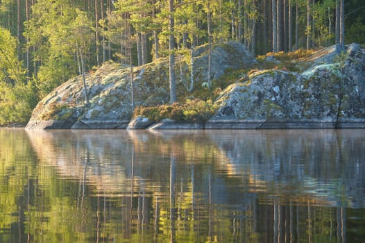 on a lake in Sweden in Smalland. Rock in foreground, blue water, sunny sky, green forests. Relaxation and silence on vacation